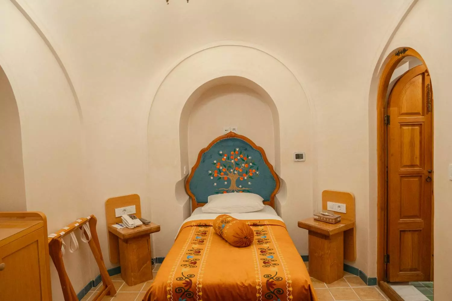 تخت یکنفره با روتختی نارنجی در عمارت آقاحسینی