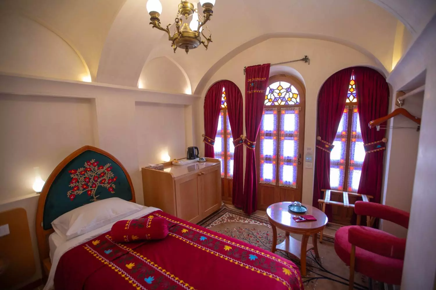 اتاق خواب با تخت قرمز و پنجرههای رنگی عمارت آقاحسینی