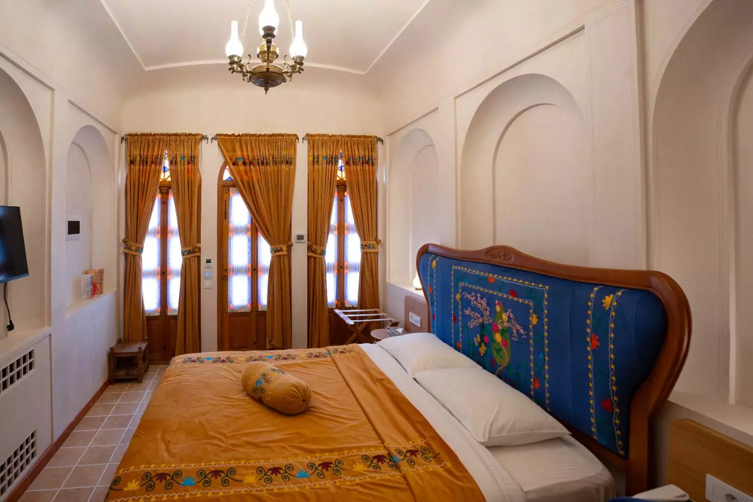 تخت اتاق عمارت آقاحسینی کنار پنجرههای بلند و پردههای طلایی
