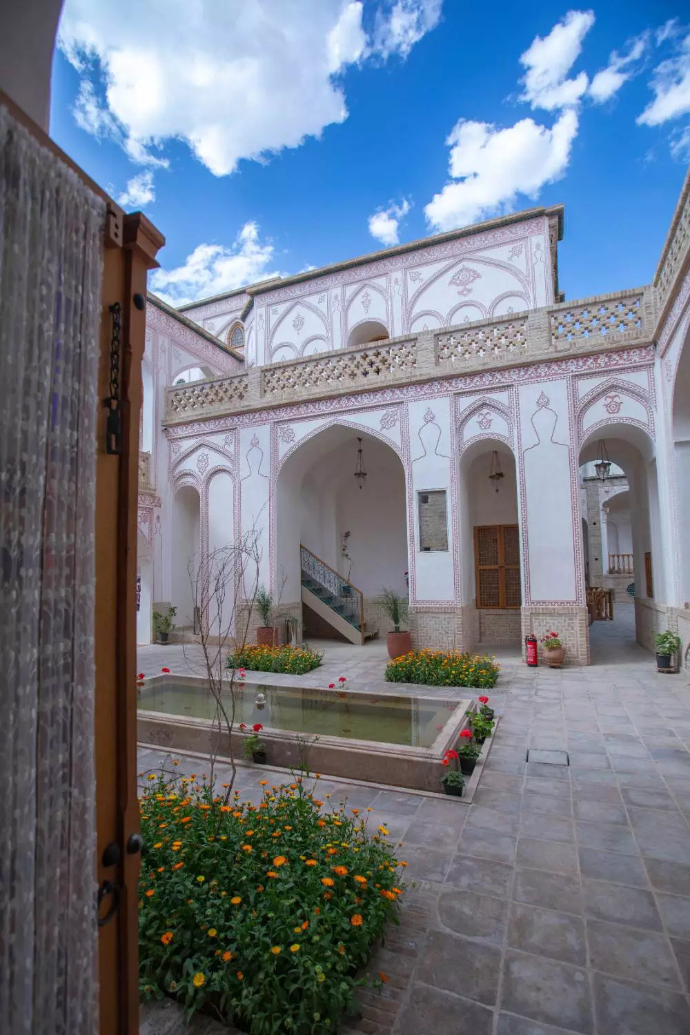 حیاط عمارت آقاحسینی با حوض و باغچههای گلکاریشده