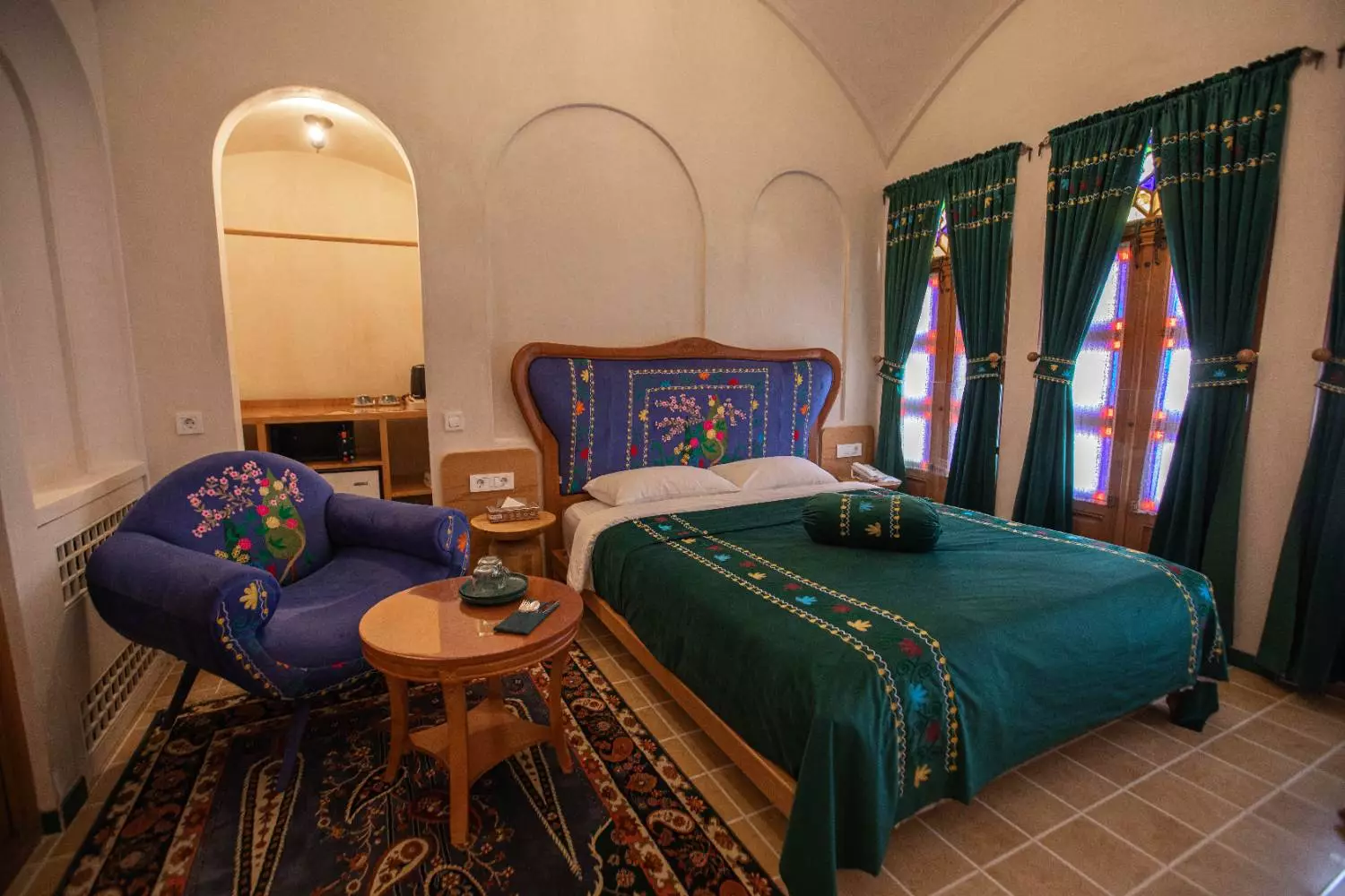 اتاق عمارت آقاحسینی با تخت سبز و پنجرههای رنگی