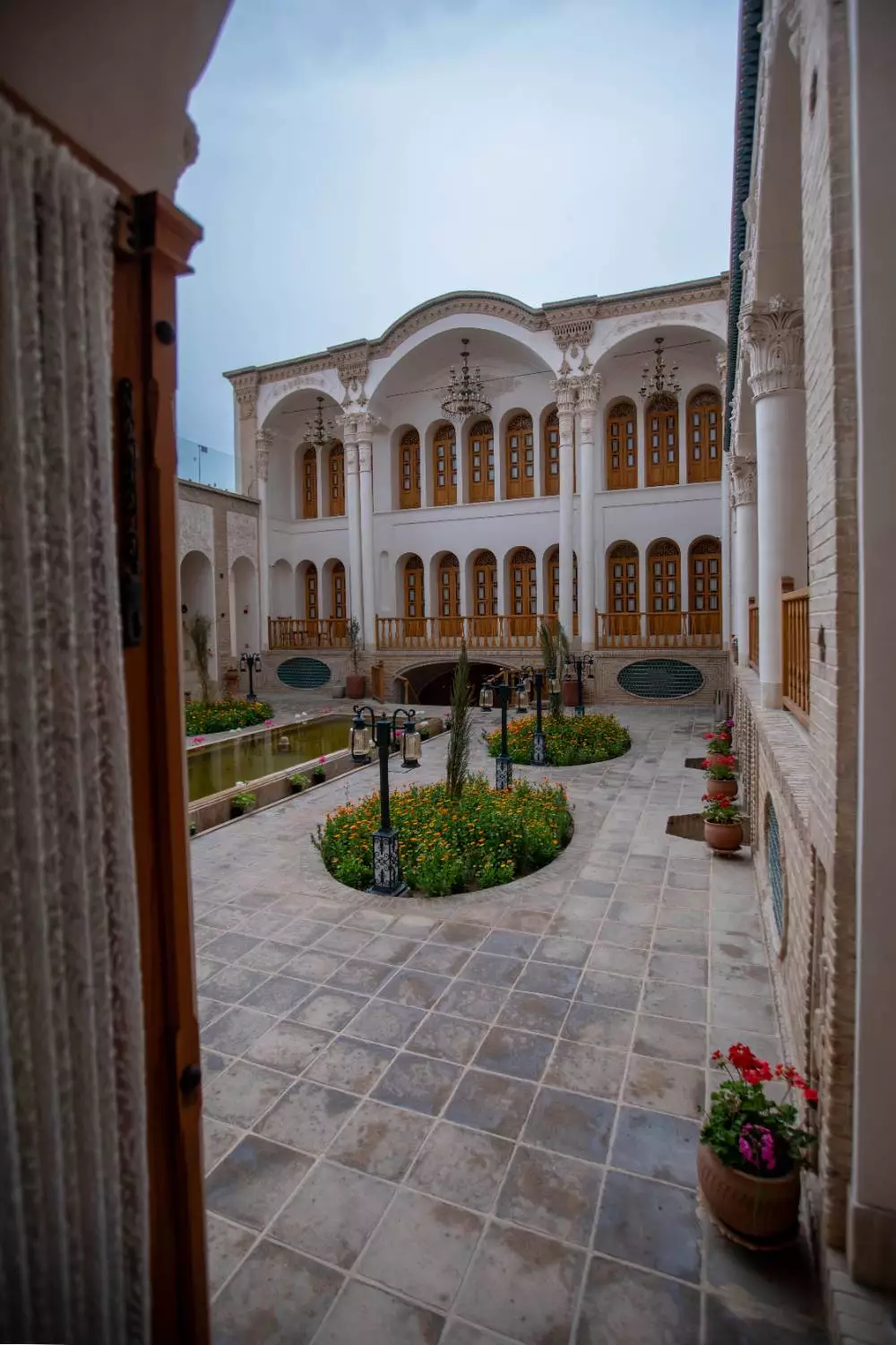 حیاط مرکزی عمارت آقاحسینی با باغچه و ایوان دوطبقه