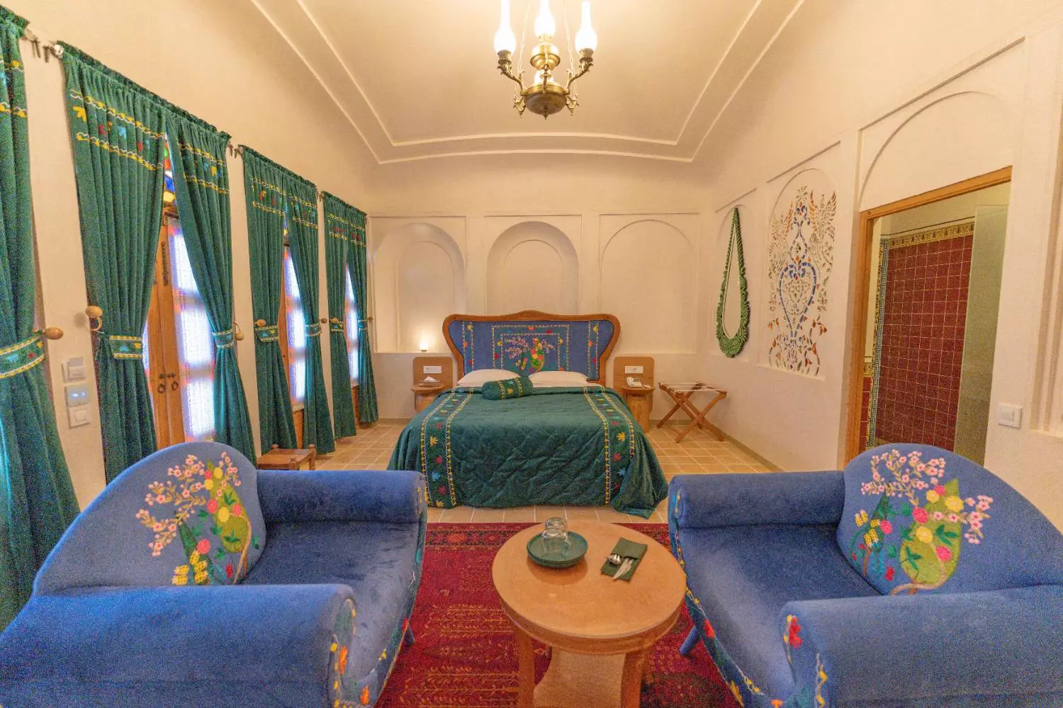 اتاق خواب عمارت آقاحسینی با تخت سبز و مبلهای آبی
