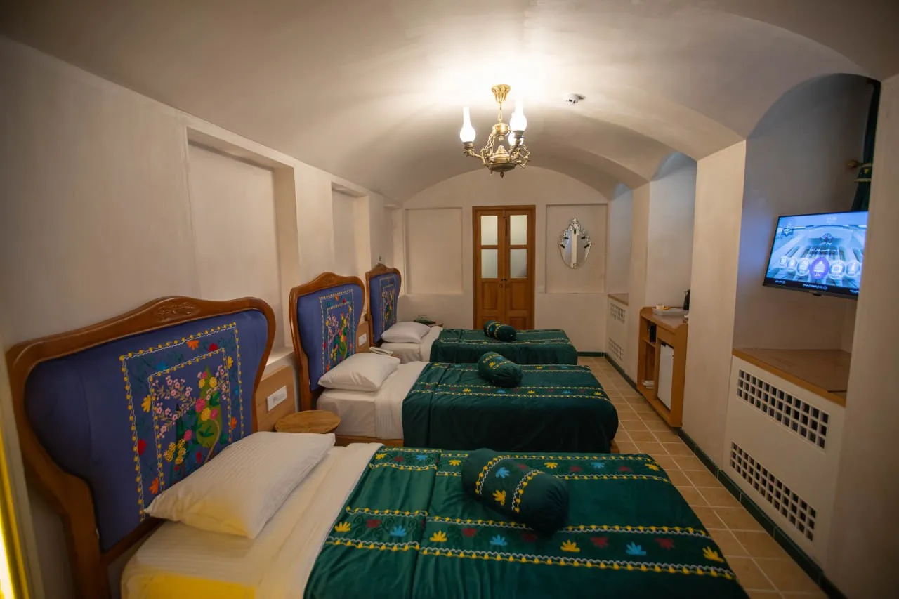 اتاق عمارت آقاحسینی با تختهای سنتی و روتختی سبز