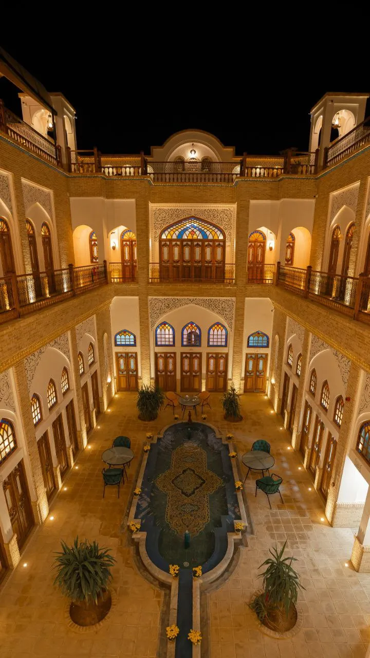 نمای شبانه حیاط مرکزی هتل ایوان با حوض و معماری آجری