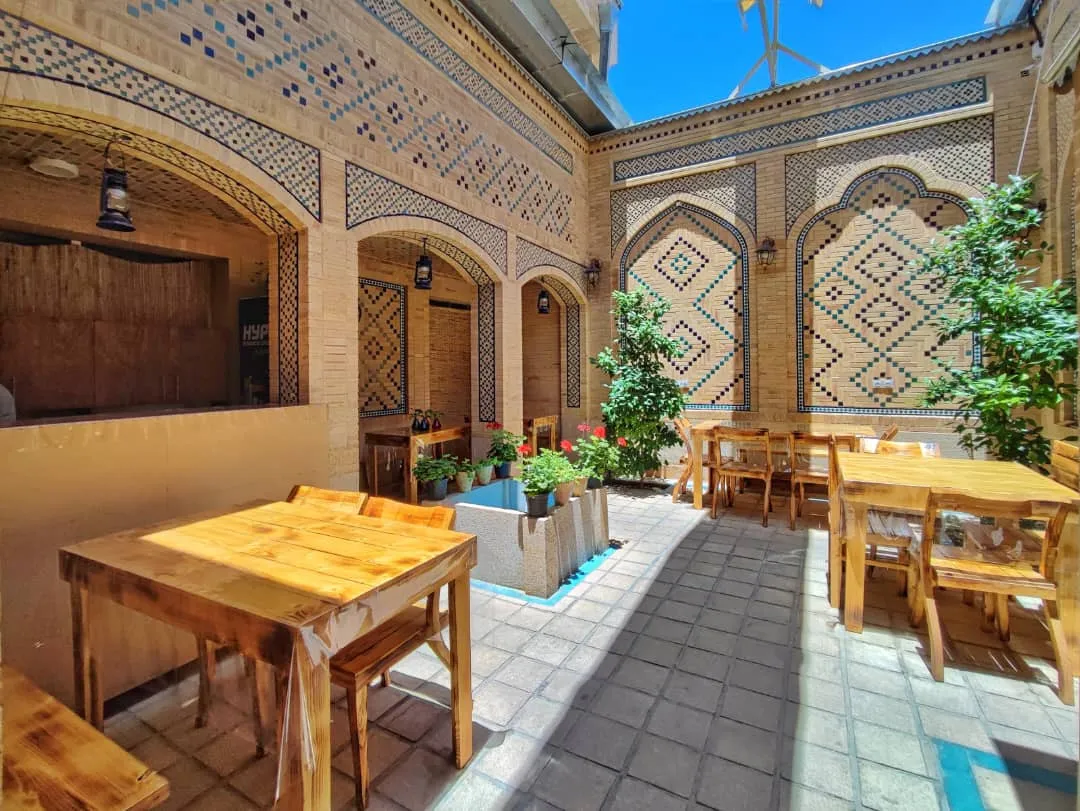 حیاط هتل عطاءالدوله با میز و صندلی چوبی