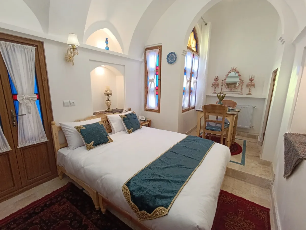 اتاق عمارت شمسه با تخت دونفره و میز غذاخوری