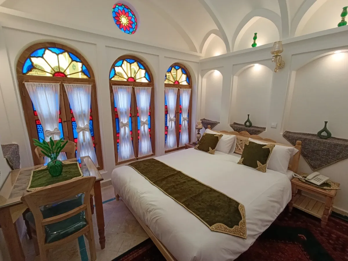 اتاق عمارت شمسه با تخت و پنجره‌های رنگی