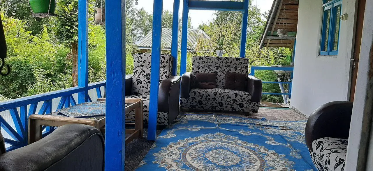 ایوان اقامتگاه کارن با مبلمان طرح‌دار و منظره سبز
