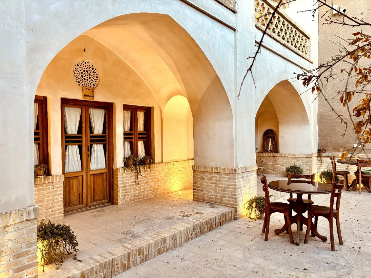 ایوان طاق‌دار سرای طاق چشمه با میز و صندلی