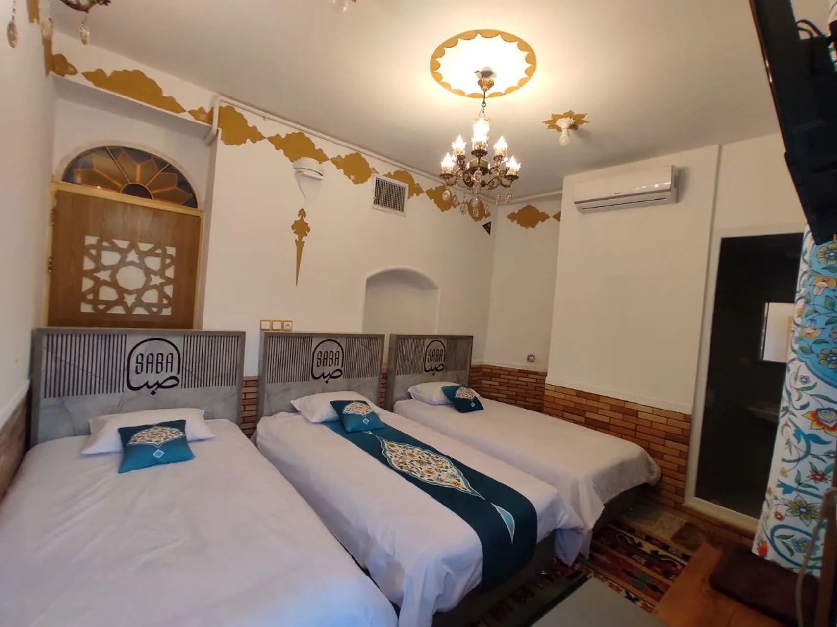 اتاق سهتخته هتل صبا با تختهای سفید و تزیینات سنتی
