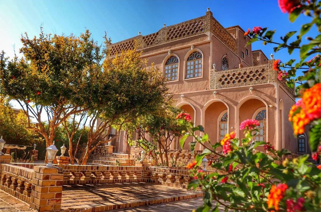 نمای آجری هتل شمس العماره میان درختان و گلها