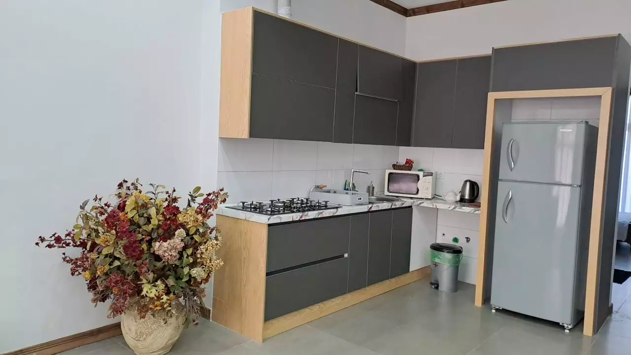 آشپزخانه با کابینت‌های طوسی و یخچال در هتل دشت