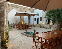 حیاط عمارت اجلال با میزهای چوبی و حوض