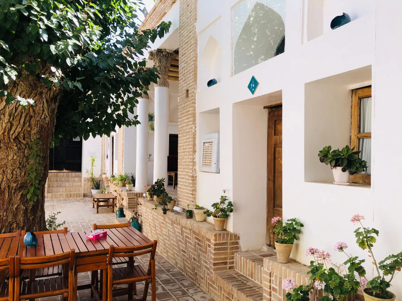 حیاط عمارت اجلال با درخت و گلدان‌های گل