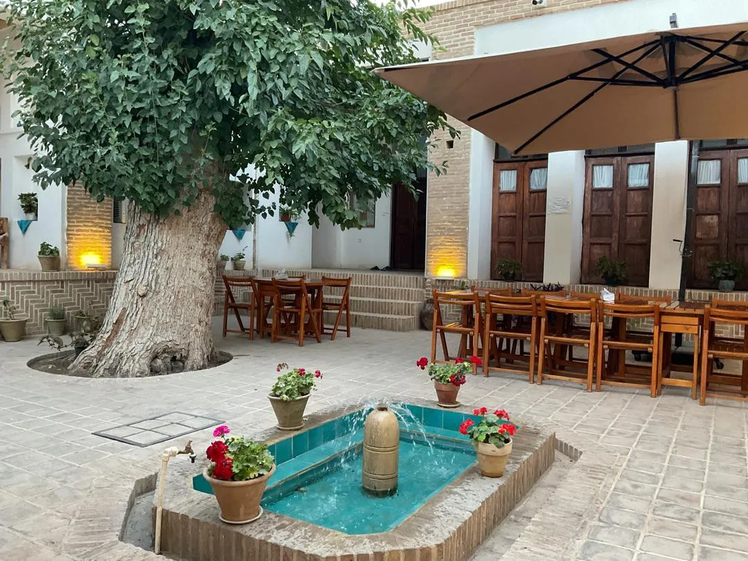حیاط عمارت اجلال با حوض و میزهای چوبی