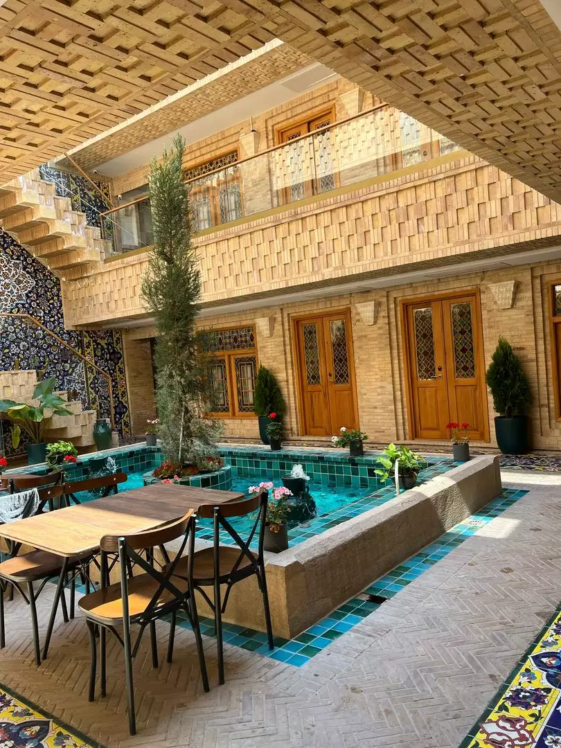حیاط ماه گیسو با حوض کاشی‌کاری و میزهای نشیمن