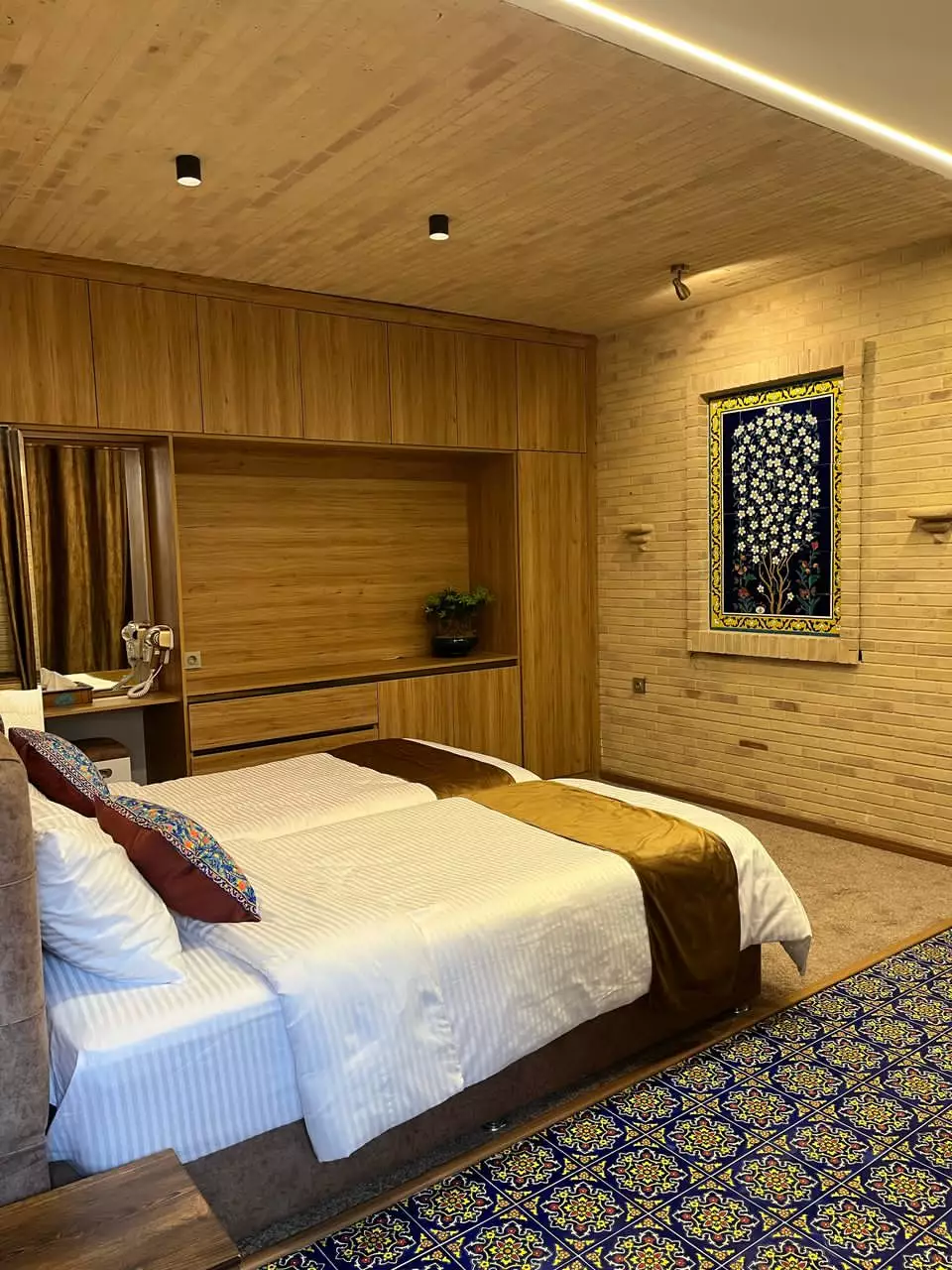 اتاق ماه گیسو با تخت دونفره و فرش طرح‌دار