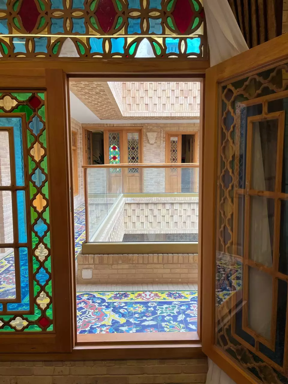 پنجره چوبی شیشه‌رنگی رو به حیاط هتل ماه گیسو