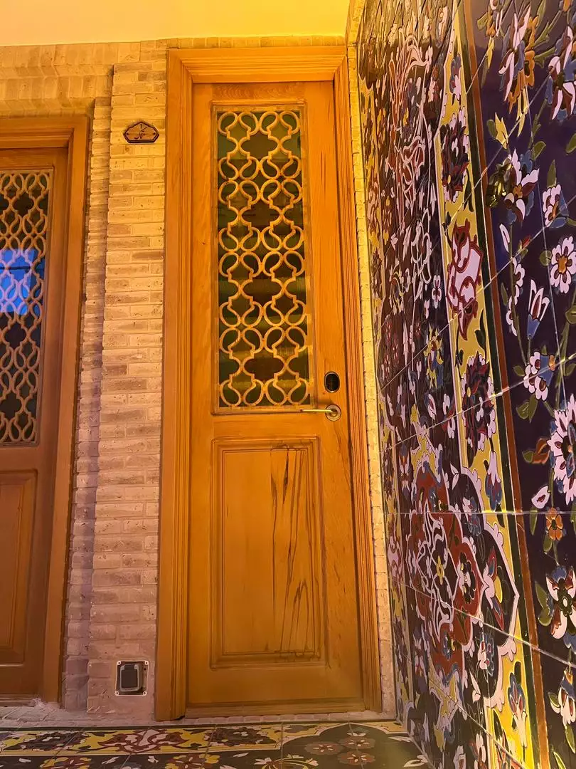 درب چوبی با شیشه مشبک و کاشی‌کاری گل‌دار در ماه گیسو