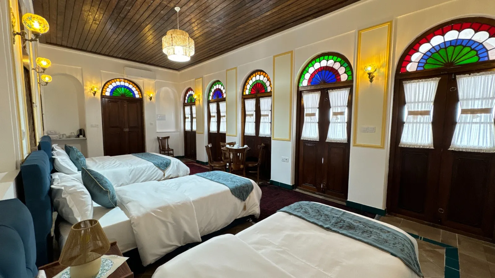 اتاق خانه گلشن با تختهای سفید و پنجرههای رنگی