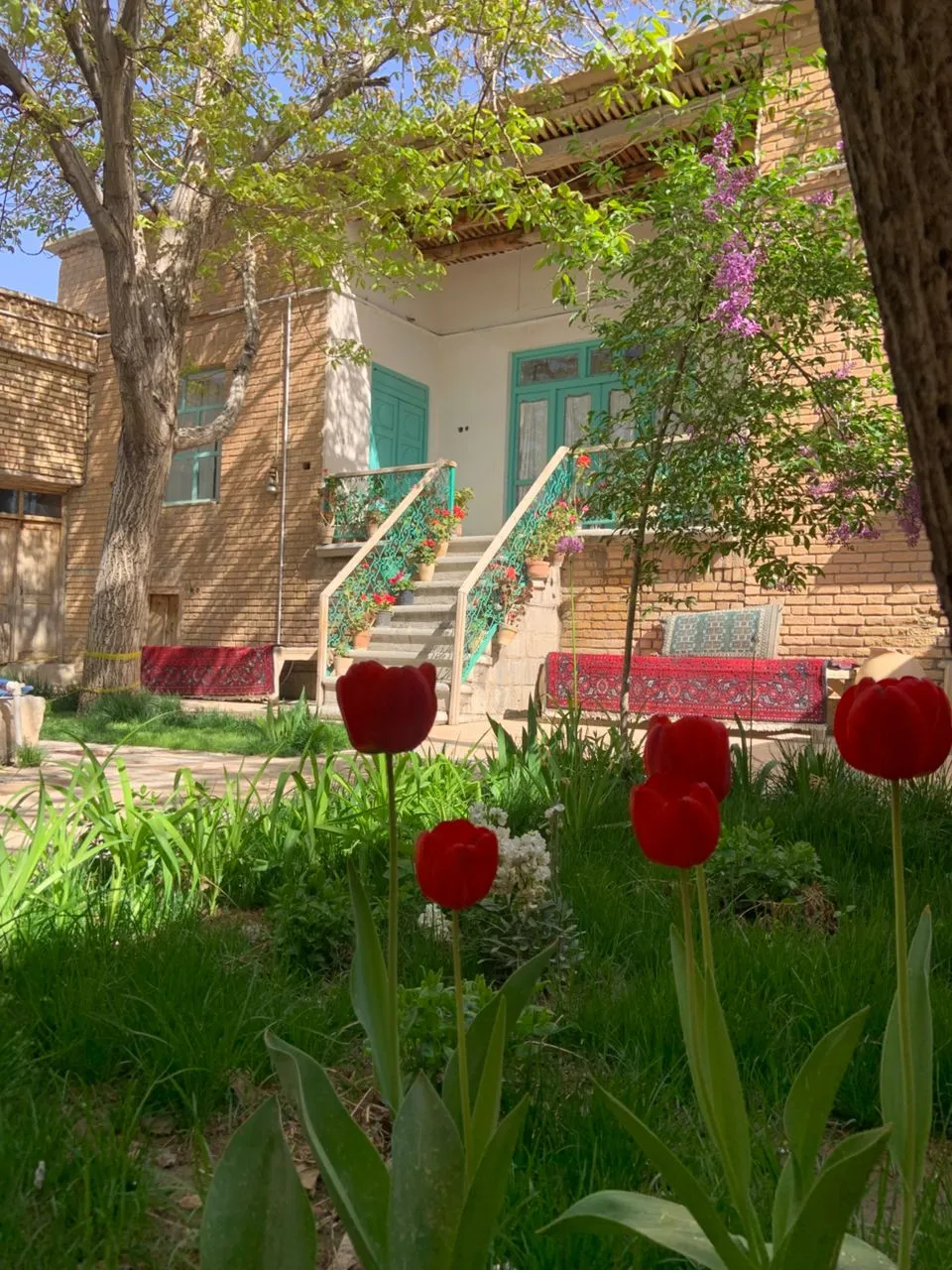 ورودی آجری خانه جواهری بوئین میاندشت میان گل‌های لاله