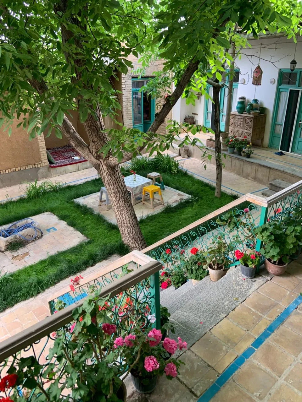 حیاط سرسبز خانه جواهری بوئین میاندشت با باغچه و گلدان‌ها