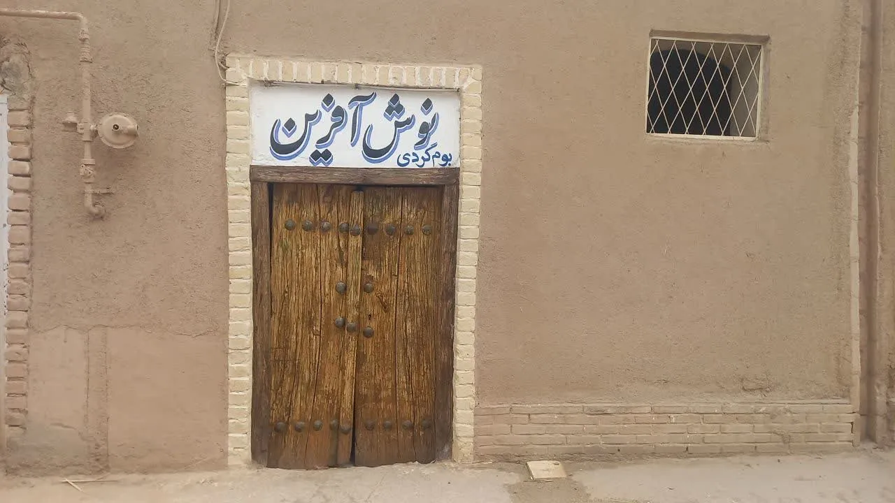 در چوبی ورودی اقامتگاه نوش آفرین در دیوار کاهگلی