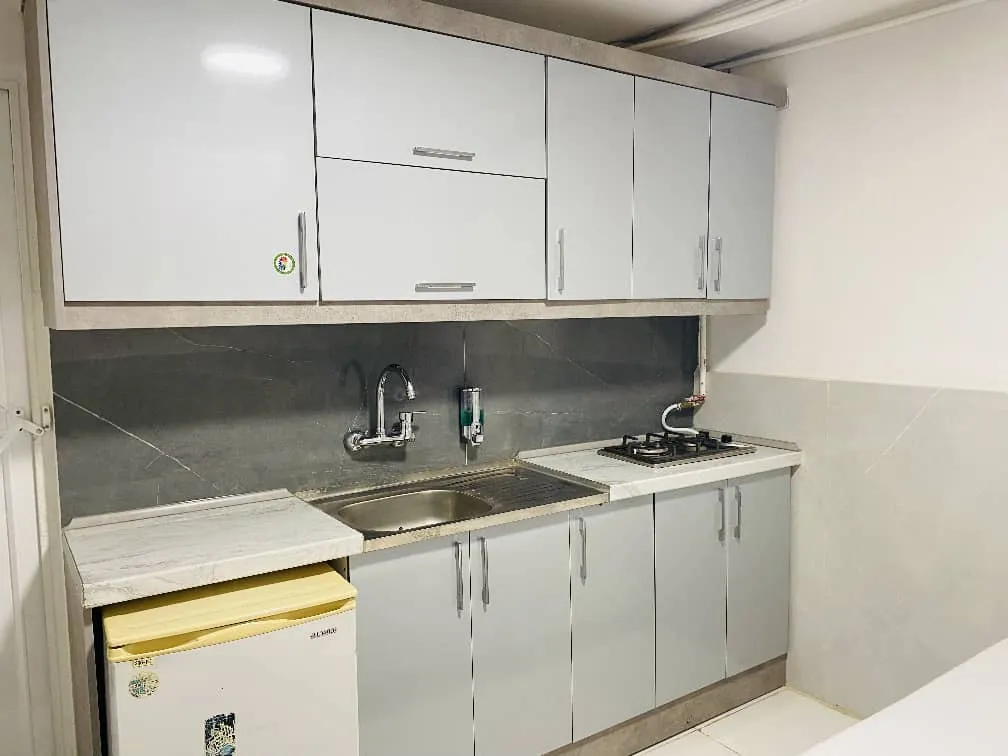 آشپزخانه هتل یارزمان با کابینت سفید و اجاق گاز