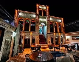نمای شبانه اقامتگاه مونگ با حیاط و میزهای چوبی