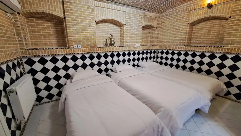 اتاق سه‌تخته با دیوار آجری و کاشی شطرنجی هتل طاوسی