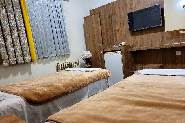 دو تخت با روتختی قهوه‌ای در اتاق هتل سیاح