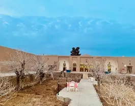 حیاط عمارت طاهری با مسیر سنگ‌فرش و درختان