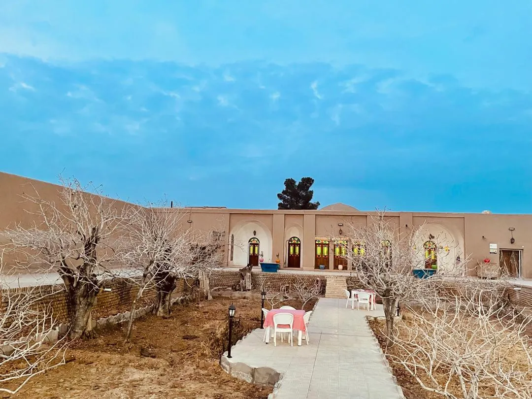 حیاط عمارت طاهری با مسیر سنگ‌فرش و درختان
