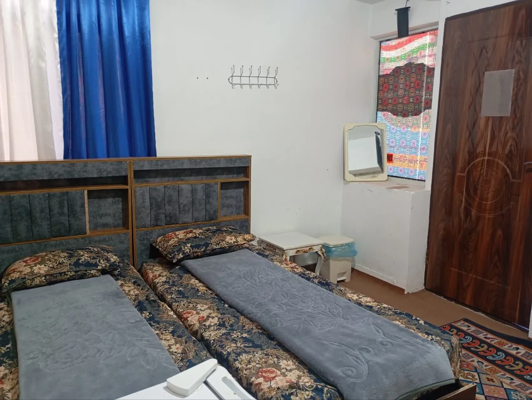 دو تخت یک‌نفره با روتختی گل‌دار در هتل دلیار
