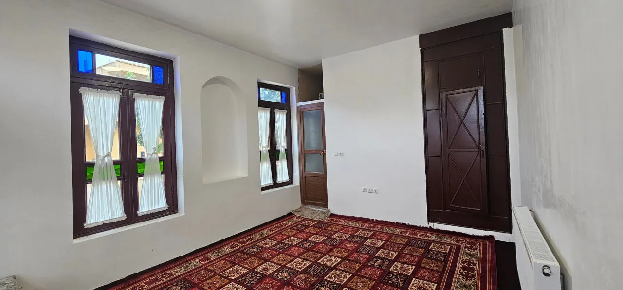 اتاق فرش‌شده عمارت پریزاد با پنجره‌های چوبی