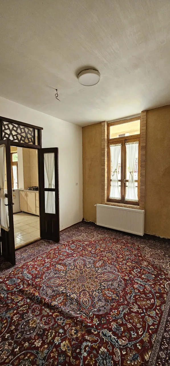 اتاق عمارت پریزاد با فرش ایرانی و پنجره چوبی