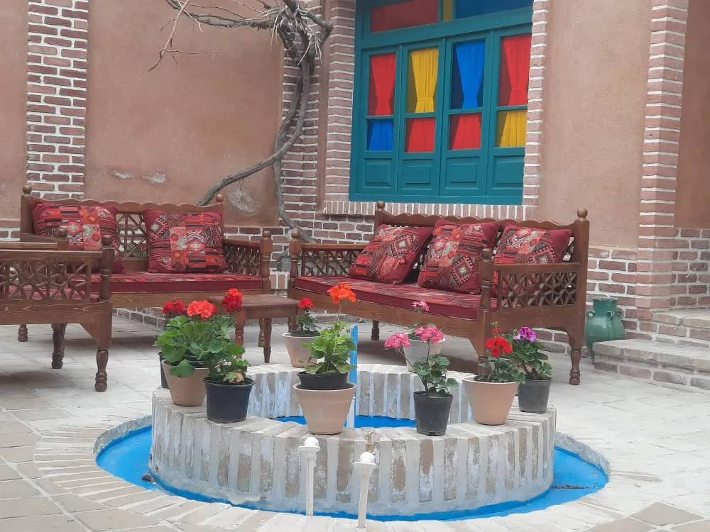حیاط کاشانه با حوض و مبلمان چوبی
