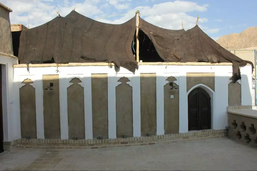 نمای بیرونی سرای ایل سنگسر با سقف چادری و کوهستان در پسزمینه