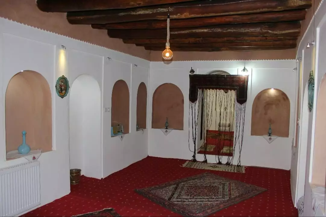 اتاق سنتی با سقف تیرچوبی و فرش قرمز در سرای ایل سنگسر