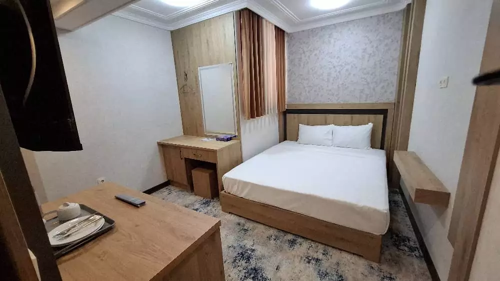 اتاق مهر آلاء با تخت دونفره و میز چوبی