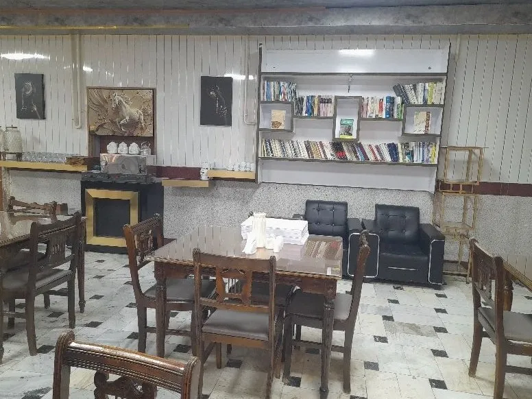 فضای نشیمن هتل پینار با میز و قفسه کتاب