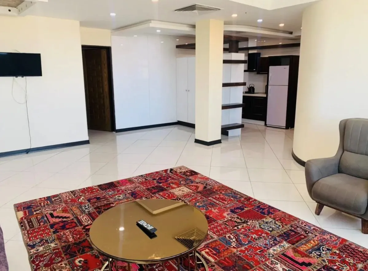 نشیمن هتل آبان با فرش قرمز و آشپزخانه کوچک