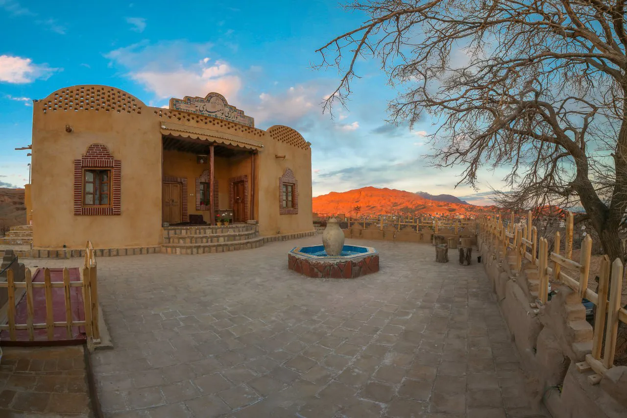 حیاط سنگ‌فرش وارگه امیدیه با حوض و نمای کوهستان