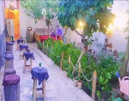 حیاط سرسبز اقامتگاه خاطره با میزهای کوچک