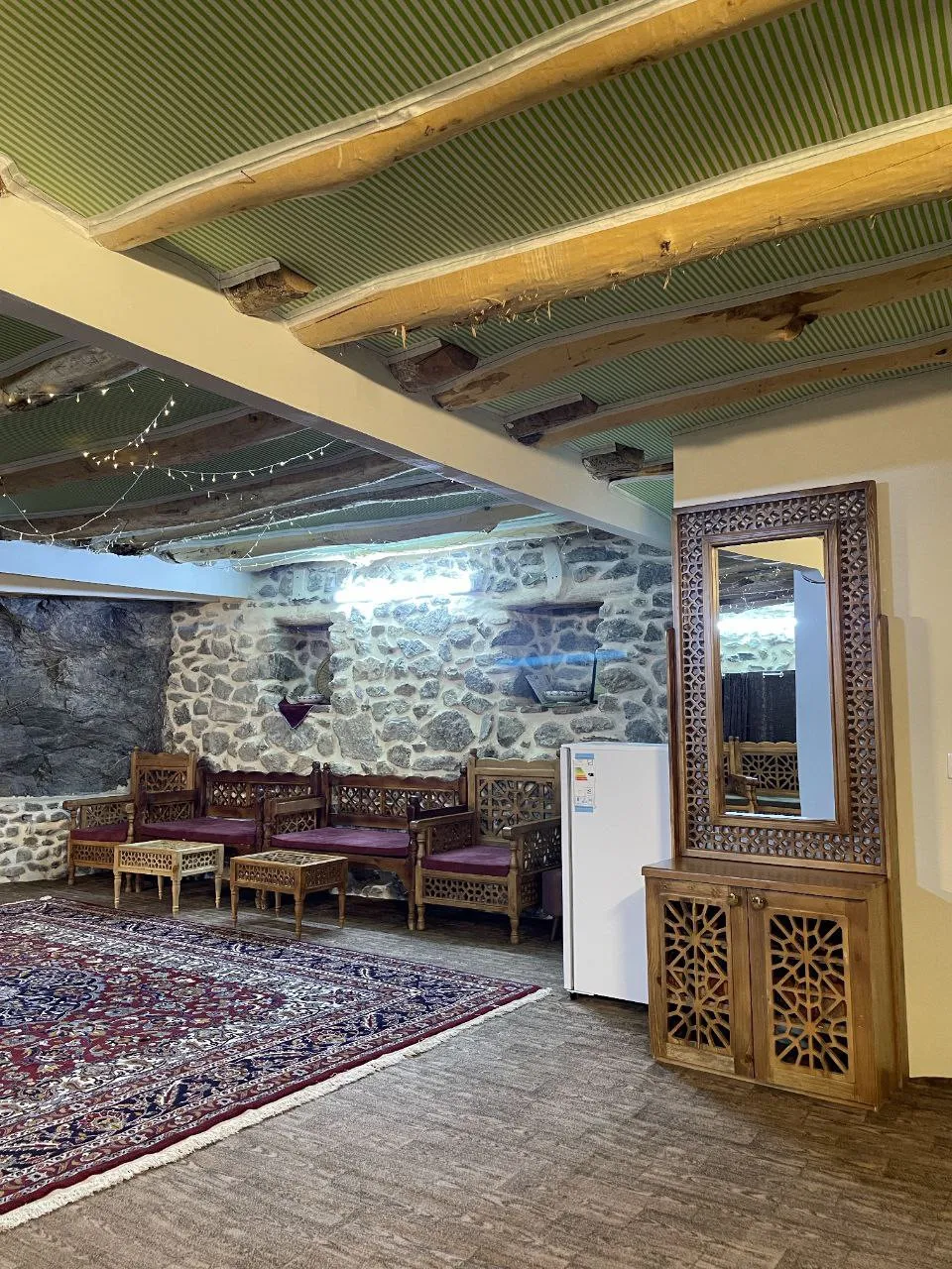نشیمن سنگی با فرش و مبل چوبی اقامتگاه بادامشک