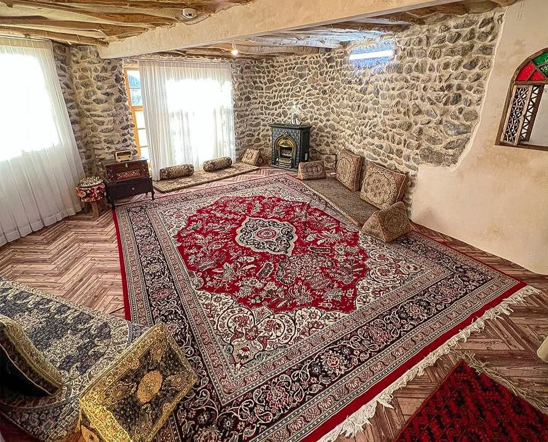 اتاق سنتی سنگی با قالی قرمز اقامتگاه بادامشک