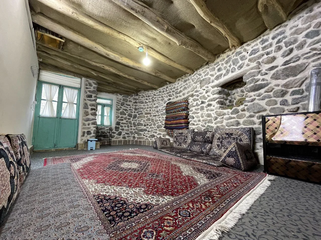 نشیمن سنگی هتل بادامشک با در سبز و فرش ایرانی