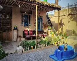 حیاط خانه کورشک با حوض آبی و باغچه گلکاریشده