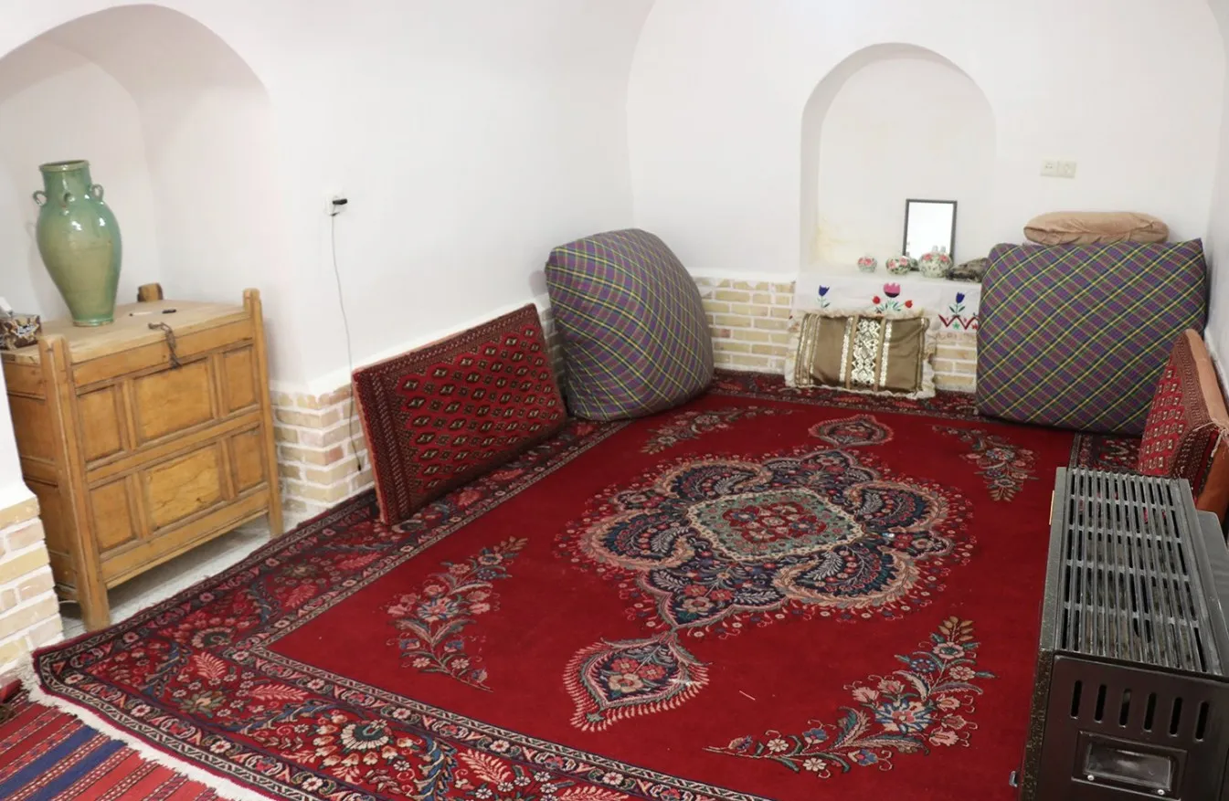 اتاق خانه کله با فرش قرمز و پشتی‌های سنتی